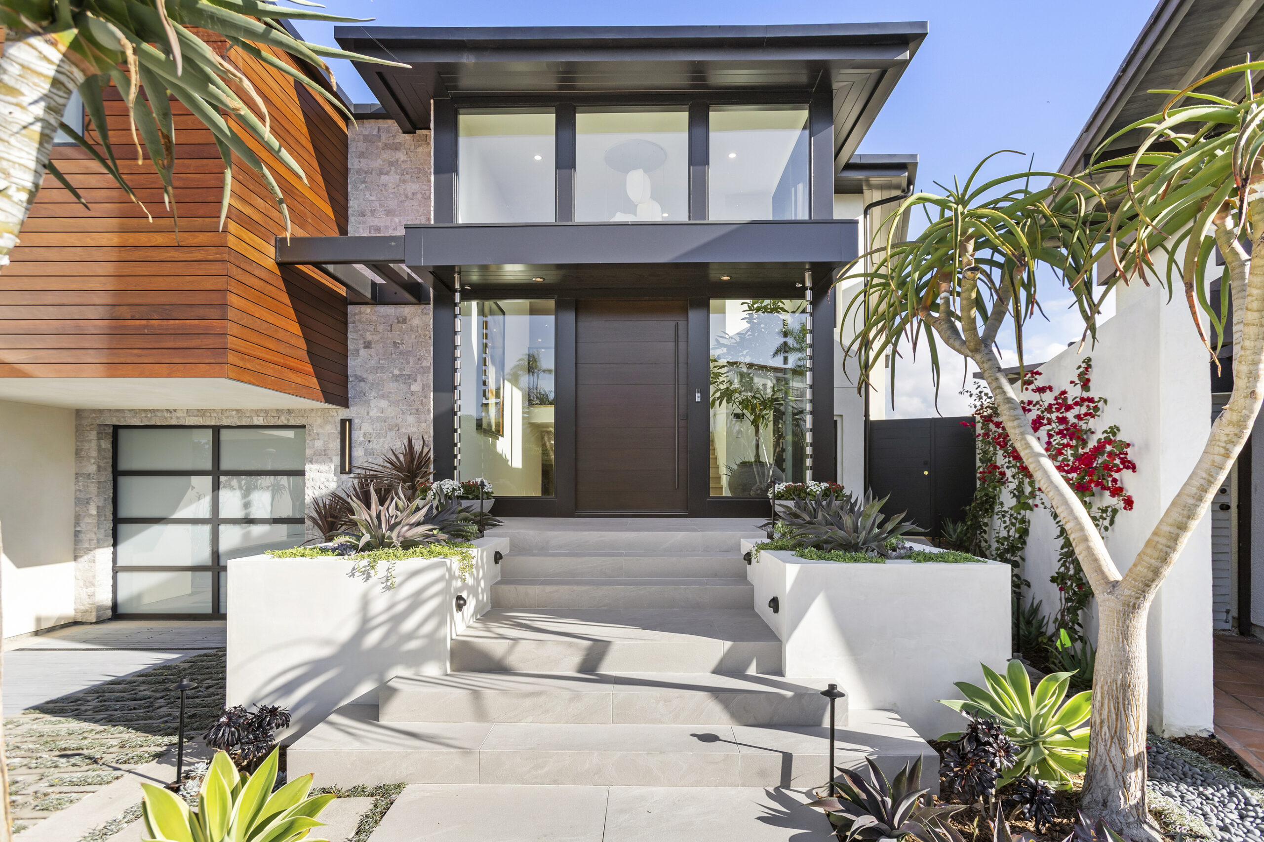 A dramatic double-height entry is framed by floor-to-ceiling glass, filling the interior with natural light and offering a seamless connection between indoors and out.
