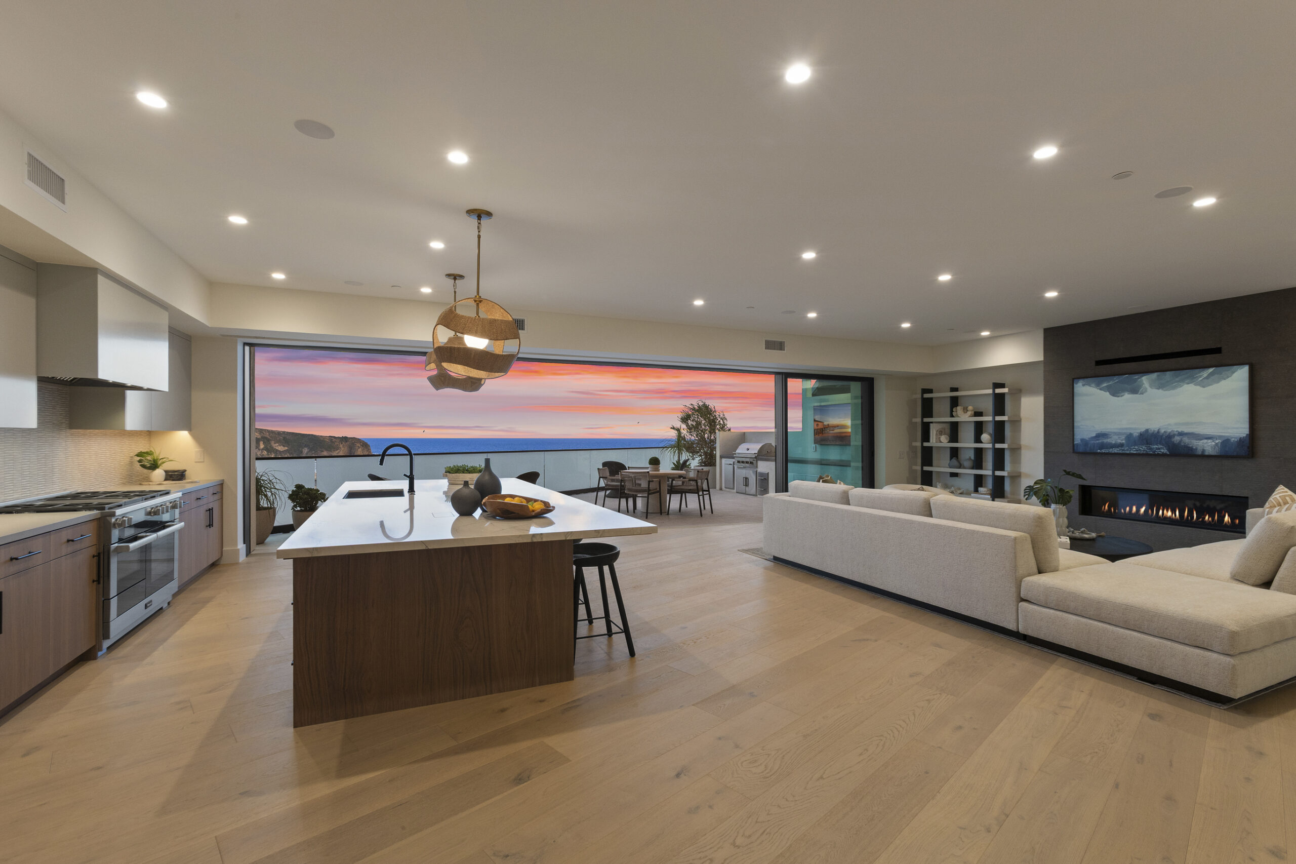 The main living level is designed for effortless entertaining, featuring an open-concept kitchen, dining, and living space that flows seamlessly to the outdoors through expansive sliding glass doors. The chef’s kitchen is anchored by a large central island and appointed with a premium appliance package, custom cabinetry, and a curated mix of quartz and quartzite countertops.